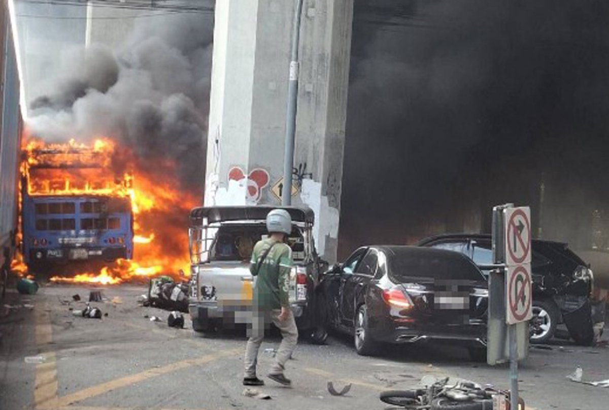 Flames rise from a passenger bus following a collision with a freight train near the Makkasan Airport Rail Link station in Huai Khwang, Bangkok on May 16, 2026. (FM91 Trafficpro)