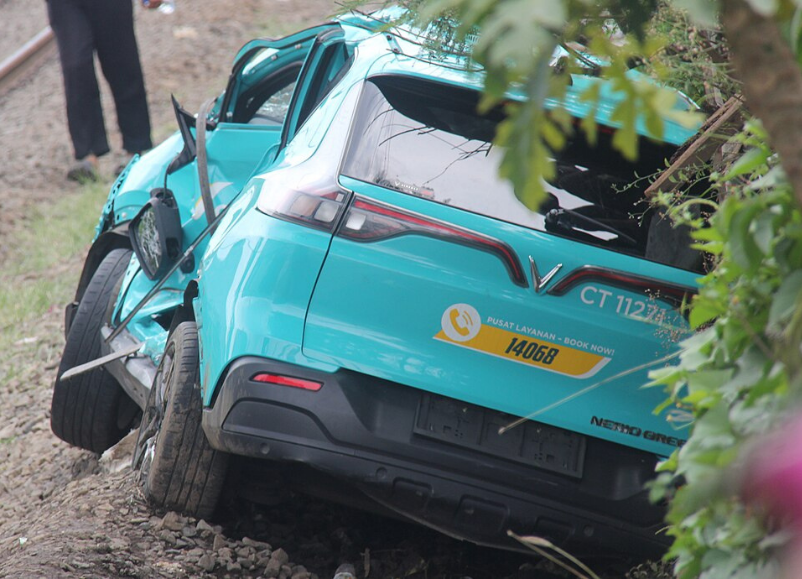 Wrecked Green SM taxi on the side of railway tracks near Ampera street railway crossing. The taxi has been struck by KA 5181B commuter train the night before. (Jauhsekali via Wikimedia)