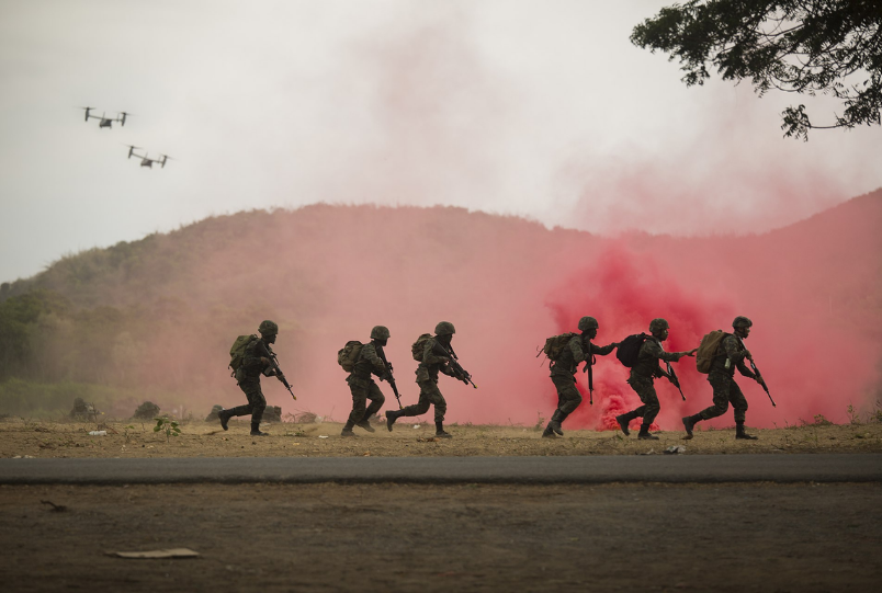 Royal Thai Marines conduct urban terrain maneuvers as U.S. Marine Corps MV‑22B Osprey aircraft fly overhead during an amphibious landing at Hat Yao Beach, Sattahip, Thailand, in Exercise Cobra Gold 2020, February 28. (U.S. Marine Corps photo by Staff Sgt. Jordan E. Gilbert)