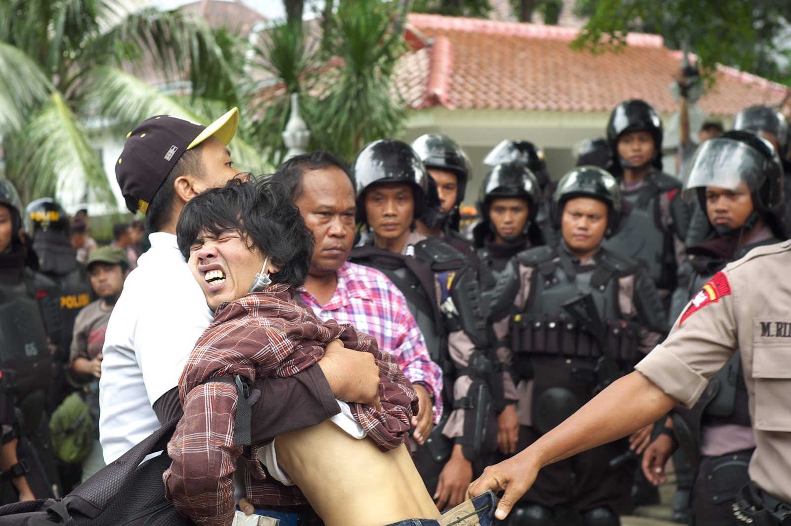 A suspected provocateur is dragged from the crowd after tensions flare between police and the KASBI Labour Union, with bottles thrown but no injuries as both sides quickly de‑escalate. (Wikimedia)