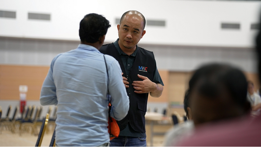 A Singaporean Migrant Workers Centre (MWC) staff member engages with a migrant worker affected by alleged unpaid salaries, on June 22. (National Trades Union Congress Singapore)