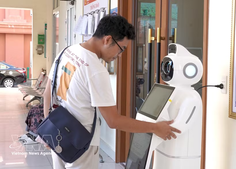 A visitor interacts with an AI-powered service robot in Vietnam as part of the country’s growing adoption of AI. (Vietnam News Agency)